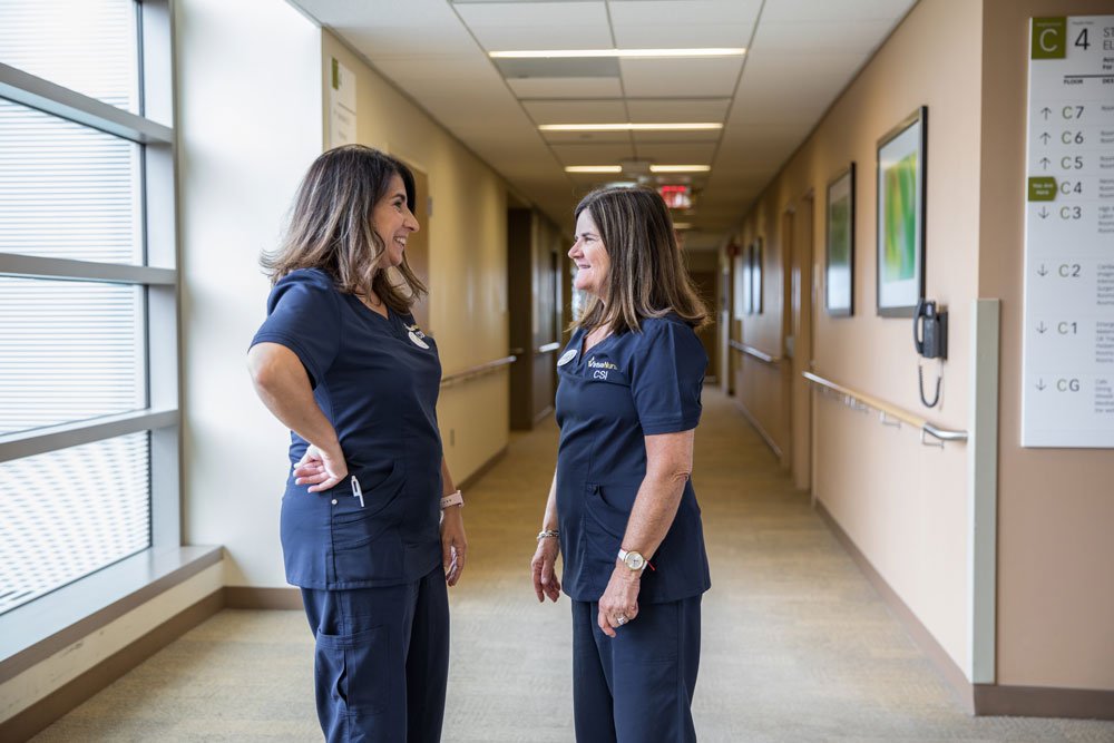 two nurses speaking in a hallway