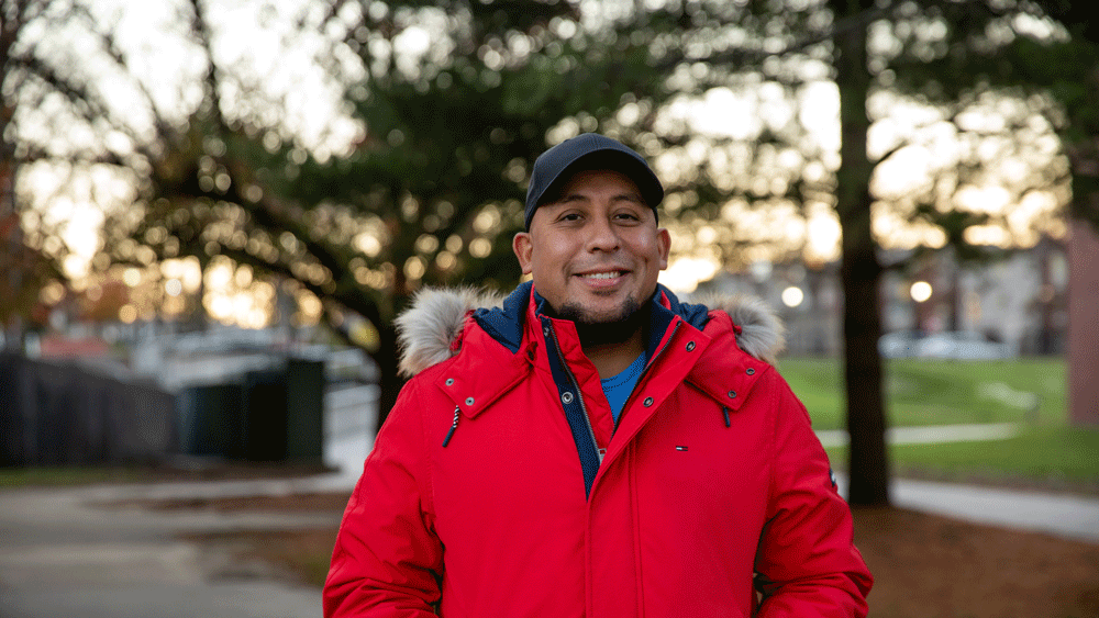 Rowan student wears red jacket outside on campus.