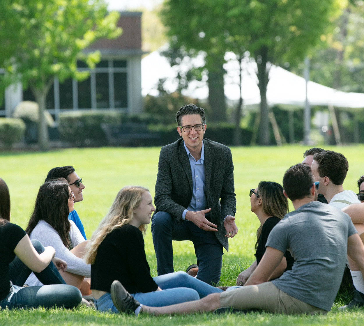 A professor lectures to a group of students outside.