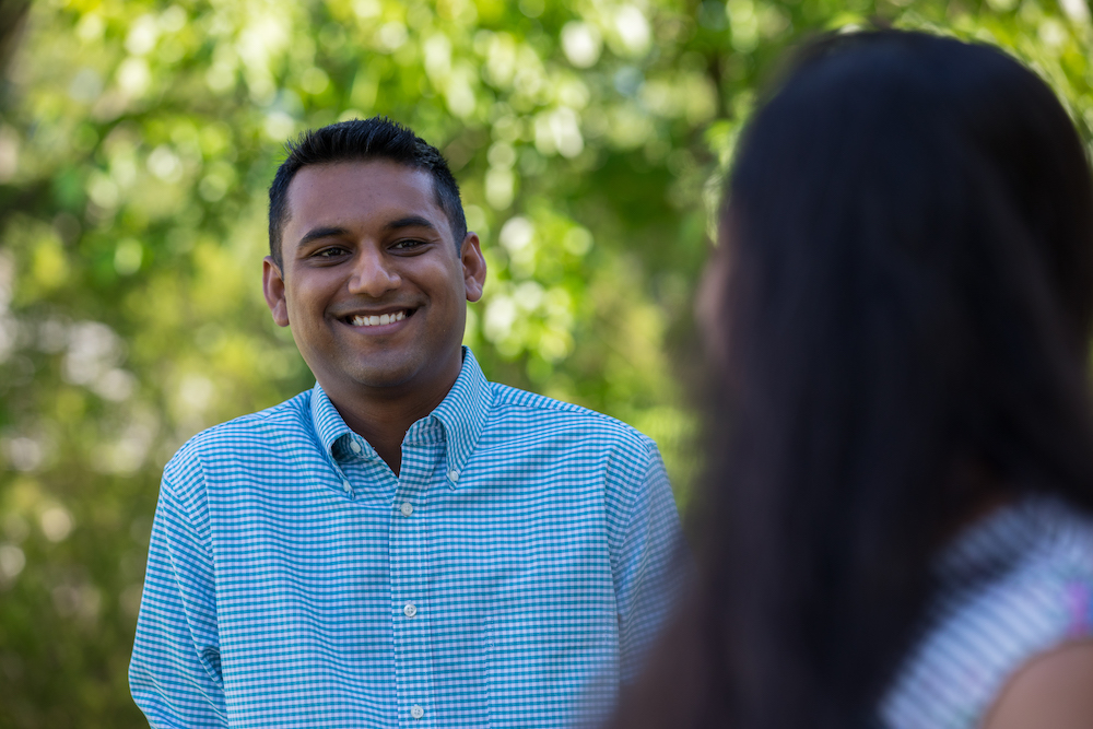 A man in a dress shirt talks with a colleague.