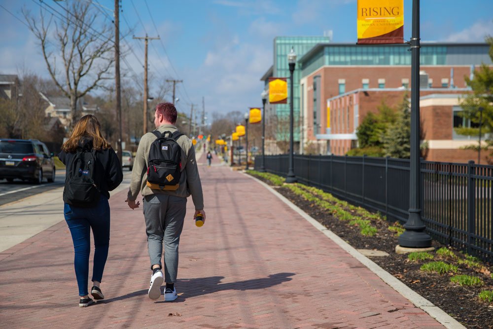 two students walk down Rowan's main campus