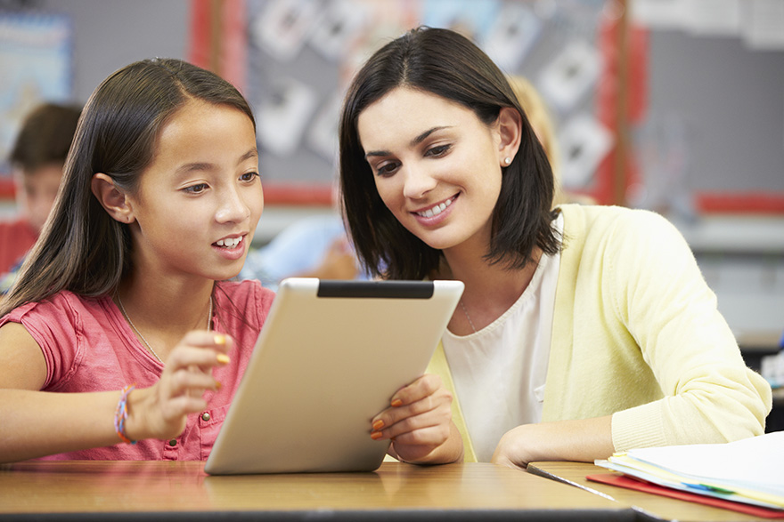 a teacher and student work together on a tablet in the classroom
