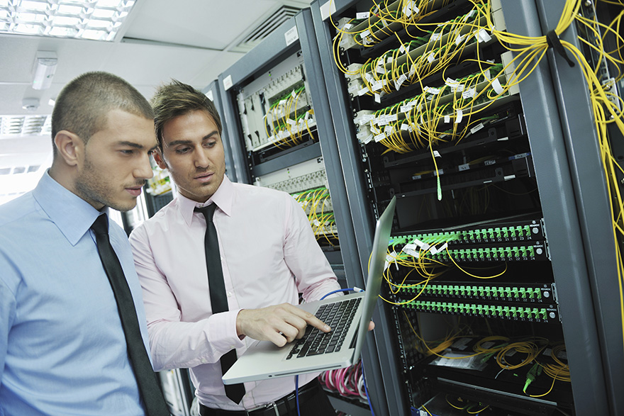 professionals working on a laptop in front of a circuit board