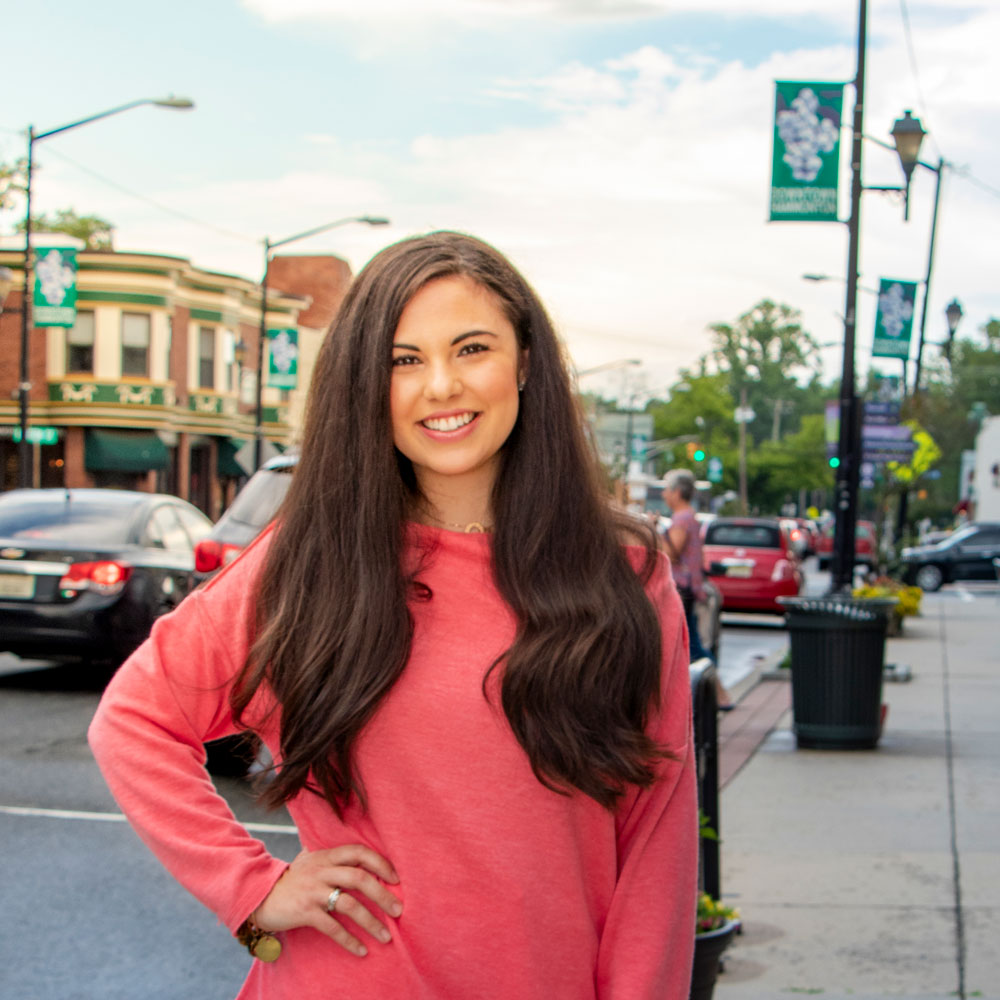 Christina D. stands in a downtown neighborhood