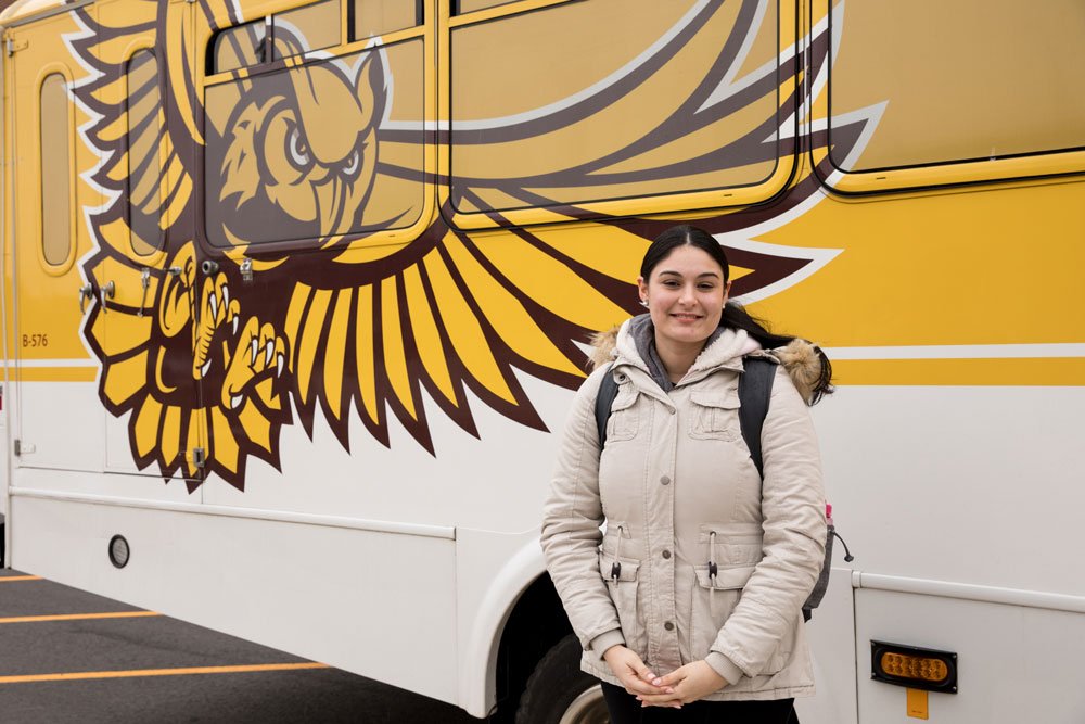 Rowan student stands next to the shuttle bus