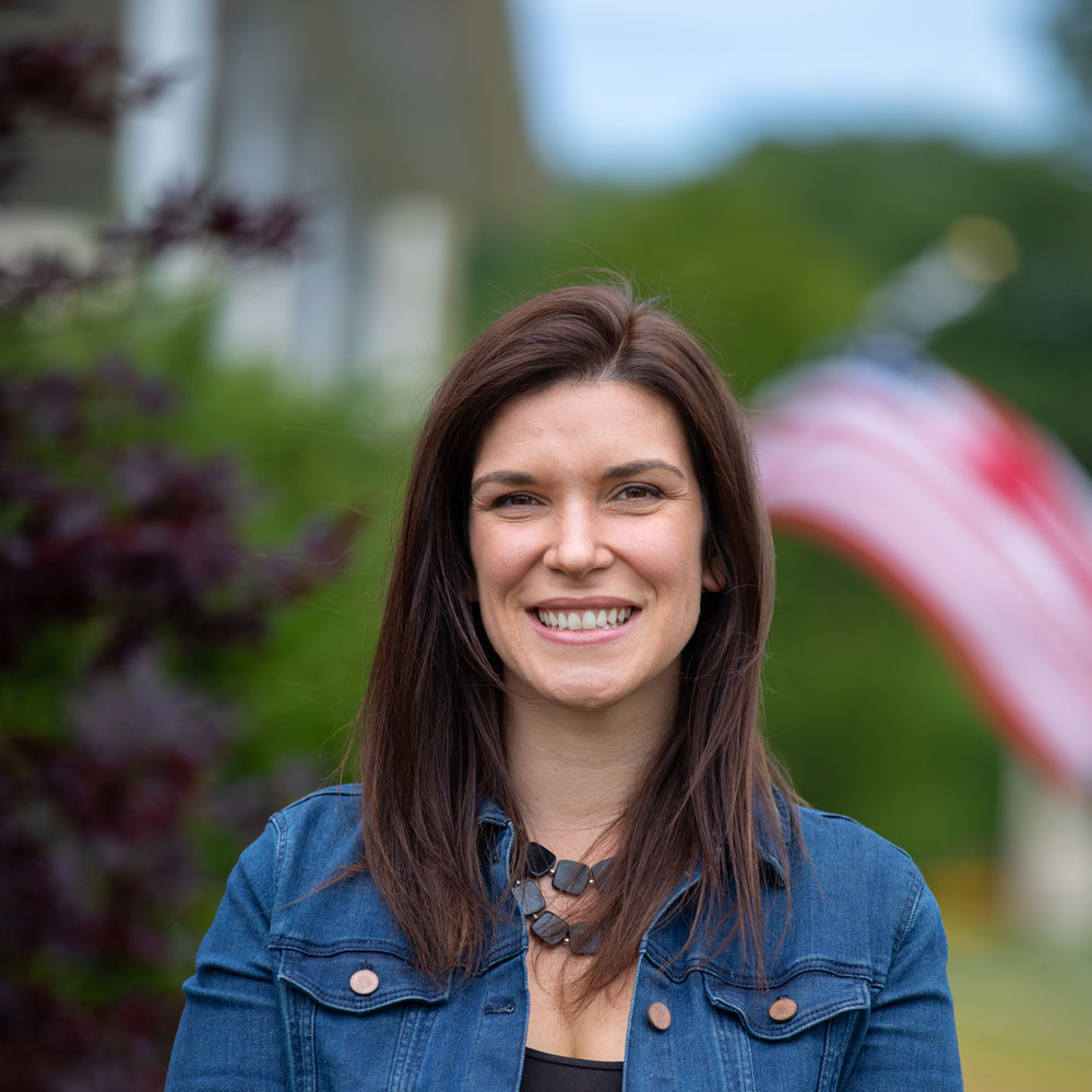 Kristi standing outside in front of an American flag