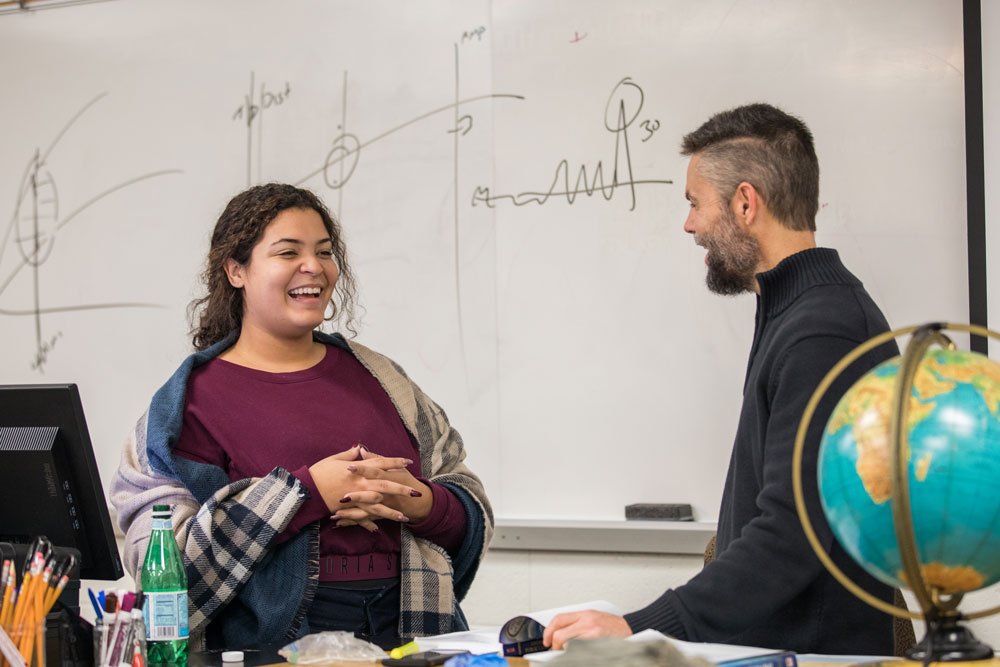 a professor laughs with a student