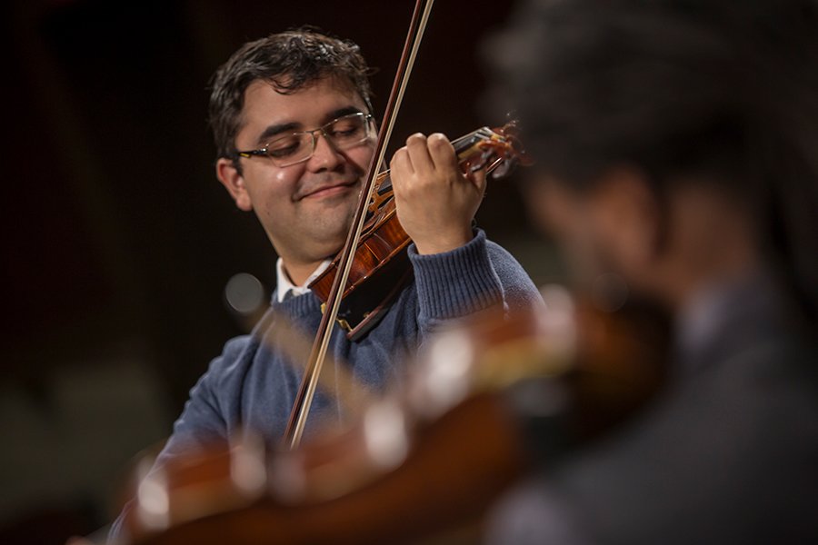 A male Master of Music student plays violin at a concert