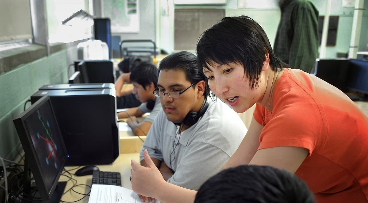 A teacher speaks with students about a class assignment