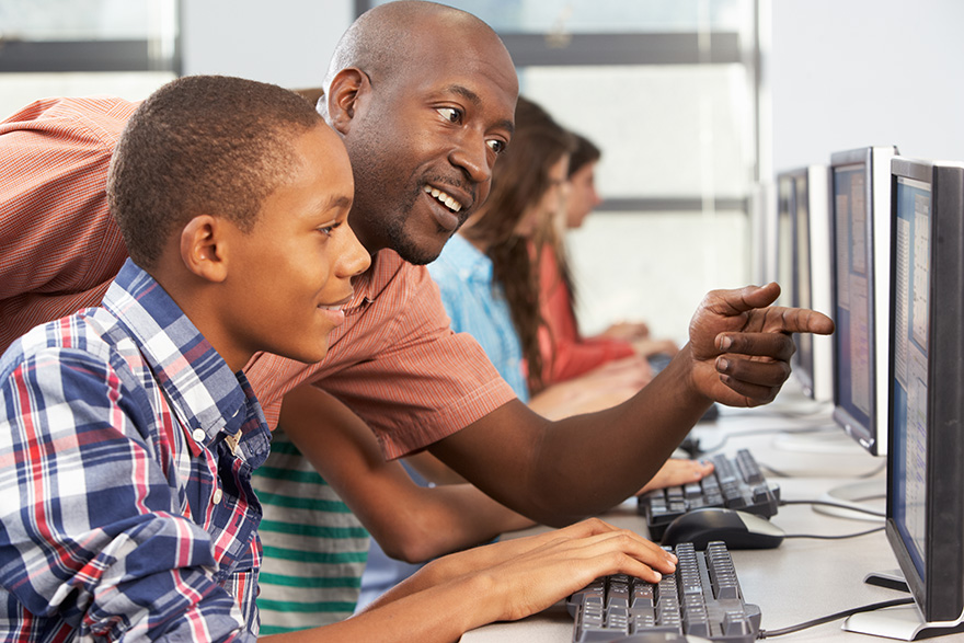 a teacher works with a student at a computer